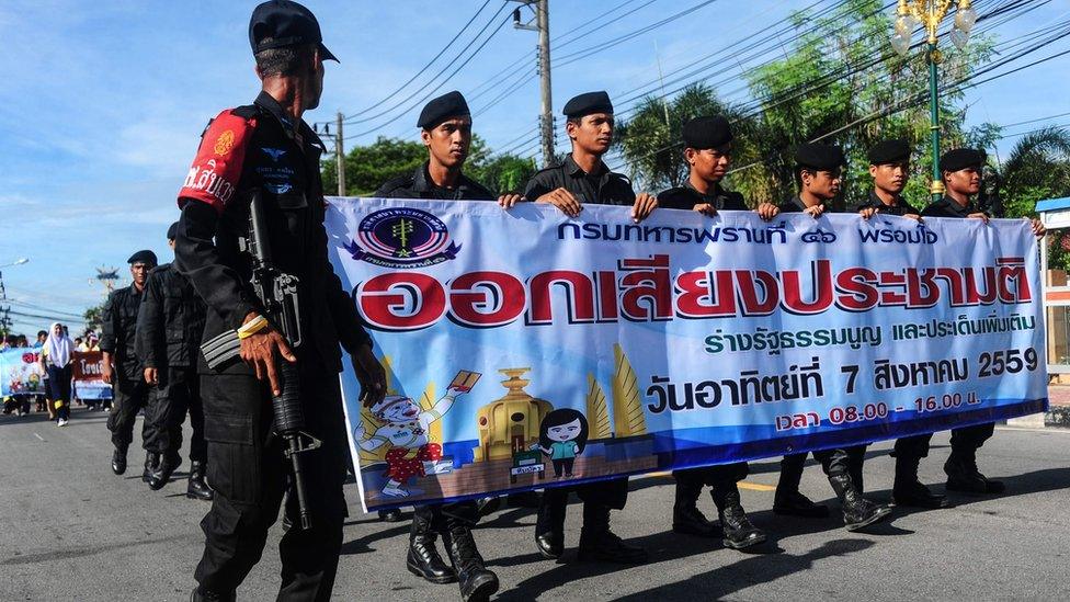 Soldiers hold banners as they march during a campaign encouraging the public to vote in the upcoming referendum on Thailand"s draft constitution in the southern restive province of Narathiwat on July 22, 2016