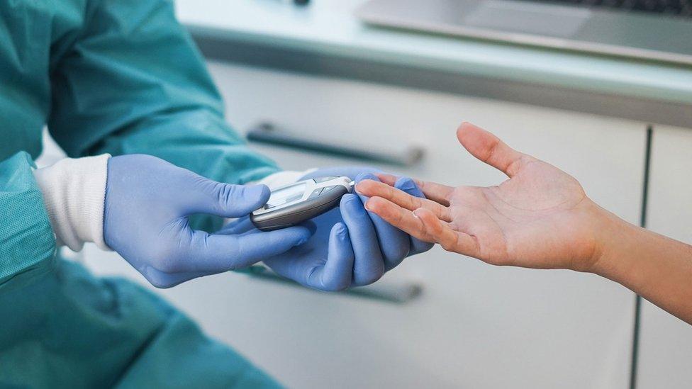 A health professional tests a patient's blood sugar level