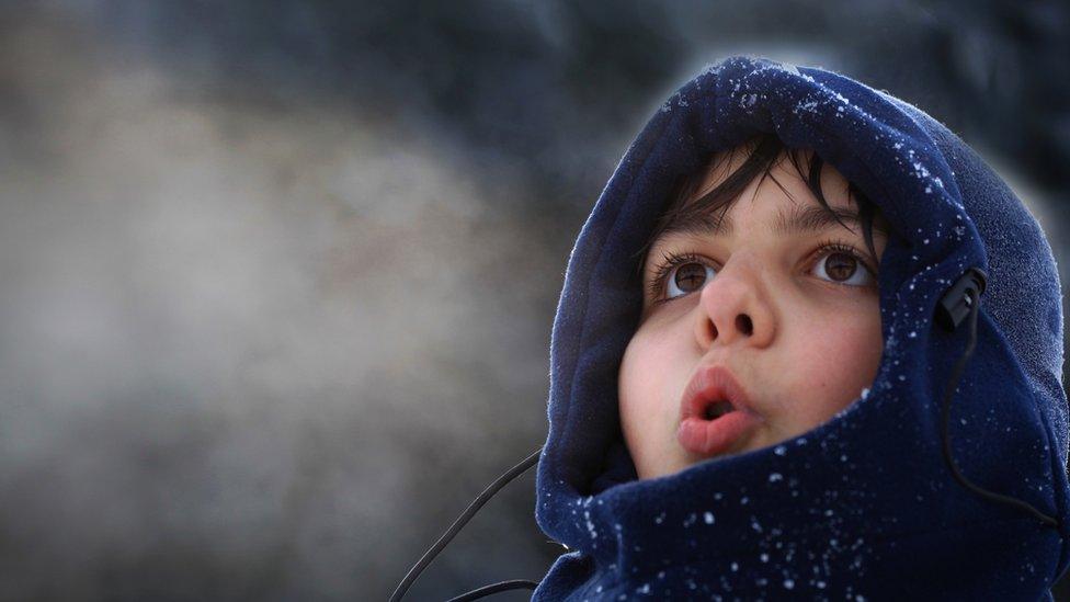 a boy breathes out into cold air