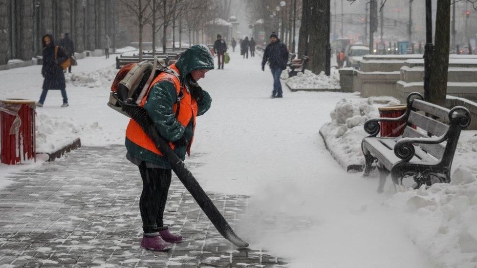 A municipal worker removes snow in central Kyiv