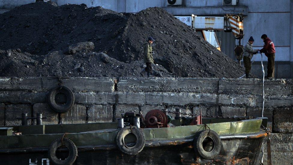 Workers next to coal mound.