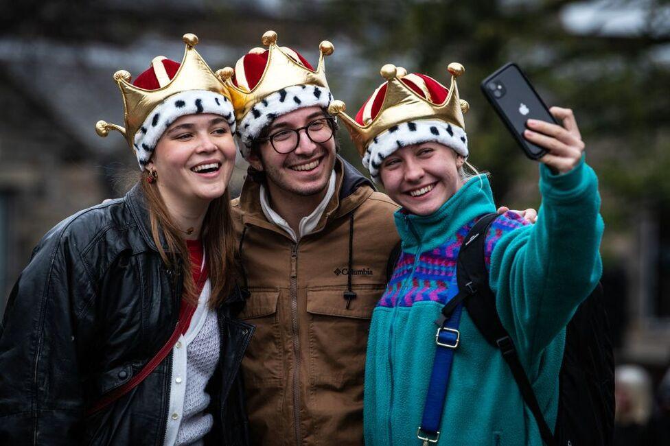 Members of the public pose wearing crown-styled hats