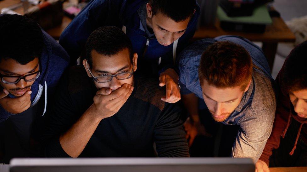 Young men gathered round a computer