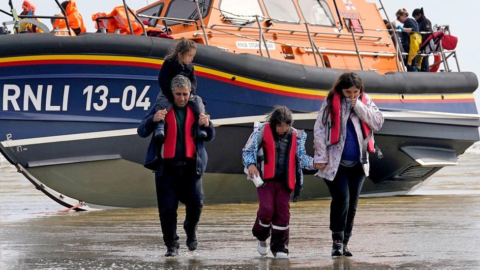 A family of supposed asylum seekers walking down a beach.