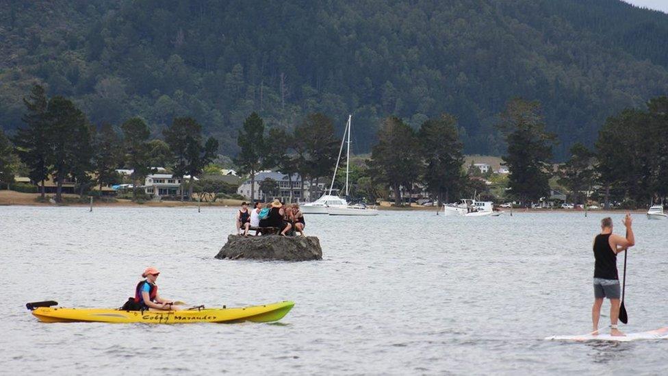 New Year revellers enjoy a drink on a special sand island they constructed earlier in the Tairua estuary on the Coromandel peninsula