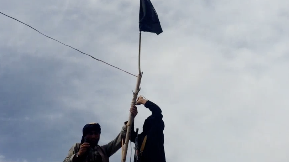 Screenshot of IS video showing two men hoisting a black flag