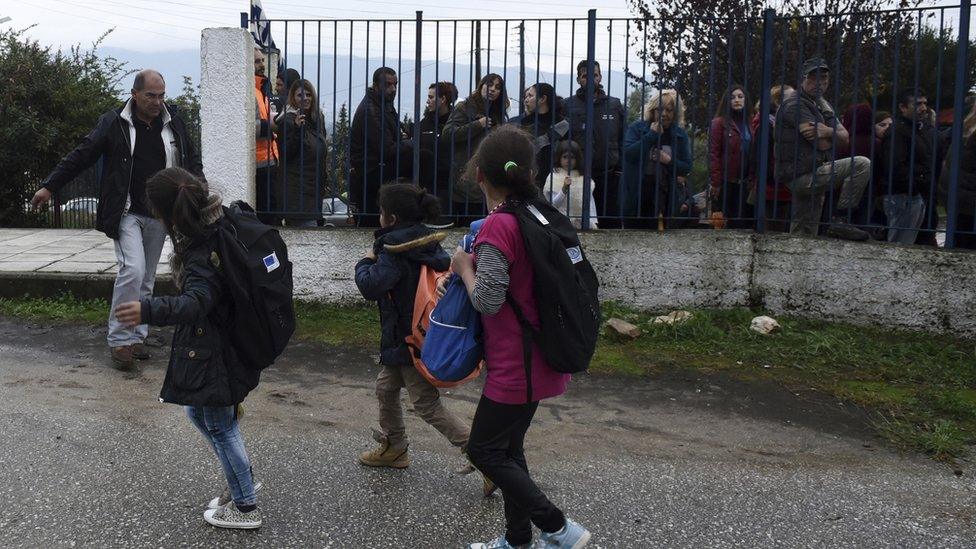 Refugee girls look at local residents as they hold a protest outside a school at the Greek village of Profitis some 35 kilometers (22 miles) east of Thessaloniki, on Monday, Oct. 10, 2016