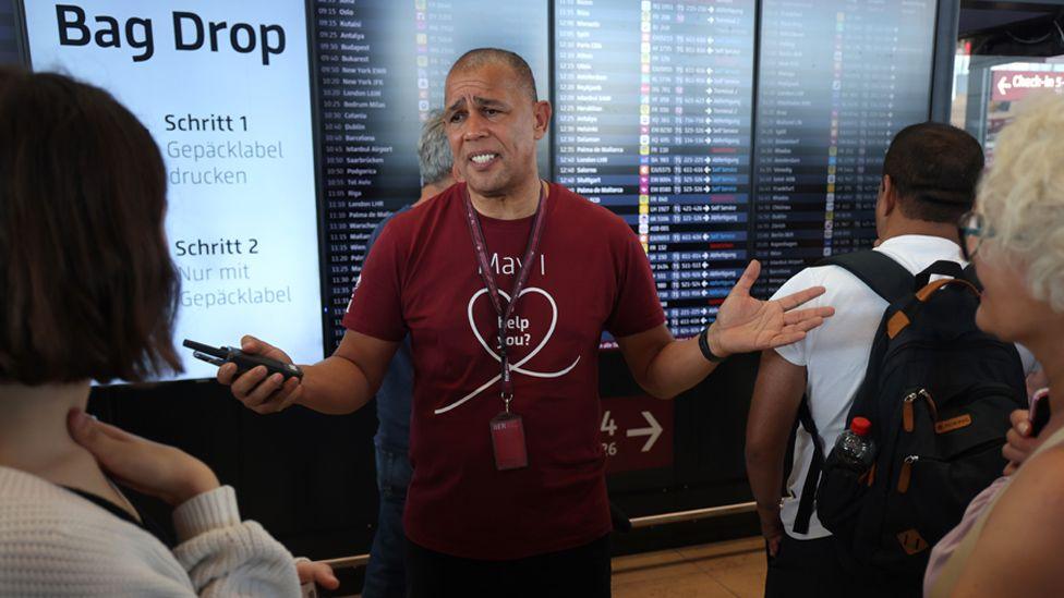 An airport employee speaks to anxious travellers at Berlin Airport 