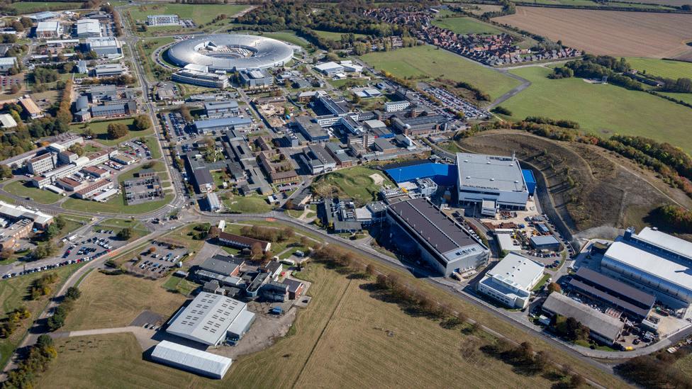 An aerial photograph of the Harwell Science and Innovation Campus, located three miles south east of Didcot. There are lots of modern, large buildings, including the big, doughnut-shaped Diamond Light Source.
