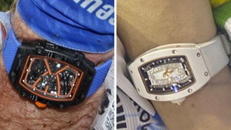 The watches. One is black with orange features on its face and a blue strap. The other is white with blue on its face.