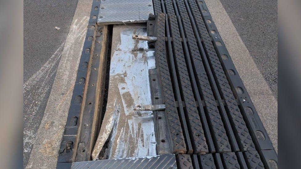 A close-up of a damaged metal joint along a motorway. The metal of the joint has been taken away and several parts are sticking out.