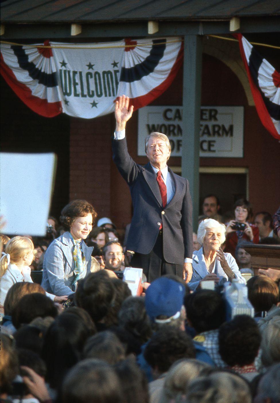 Newly elected President Jimmy Carter with his wife and mother salutes the crowd of supporters at a victory rally in his home town of Plains Georgia 