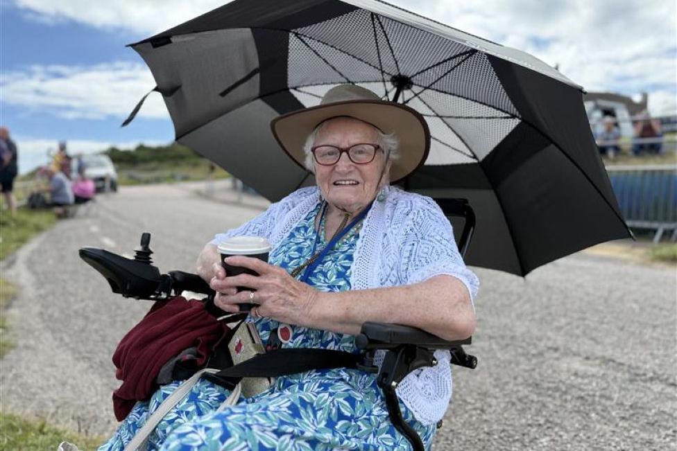 Woman sitting under an umbrella and smiling at the camera.