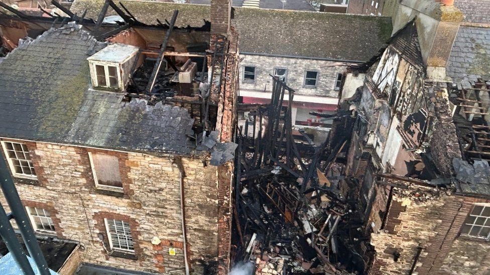 Pile of charred timber collapsed into a building in a terrace.