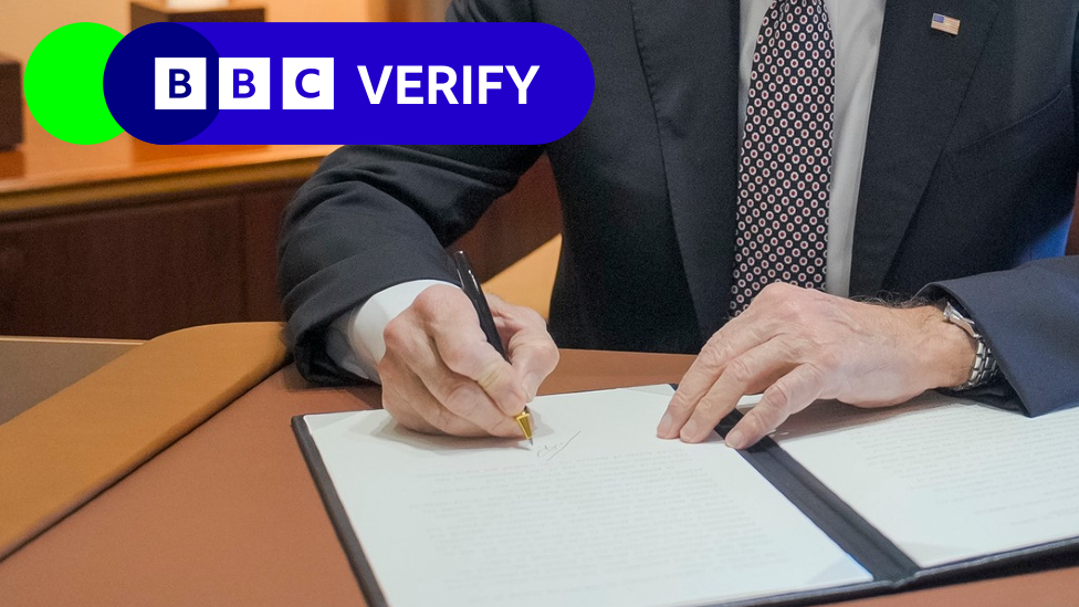 Close-up of President Joe Biden signing a pardon while on Air Force One. The BBC Verify logo appears in the top corner.