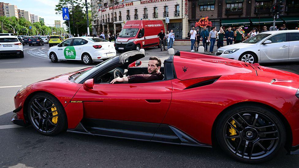 Tristan Tate driving a red sports car in Bucharest, 2024