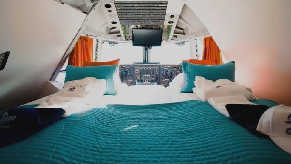 A hotel bed made on the inside of a plane cockpit. 