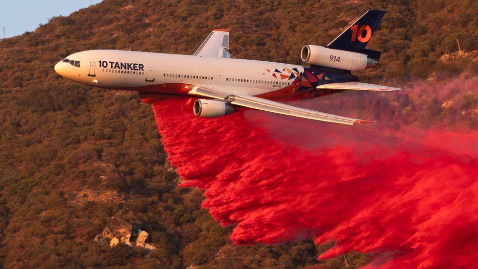 A plane drops bright red fire retardant during the Eaton Fire near Altadena, California, US, on Monday 13 January, 2025