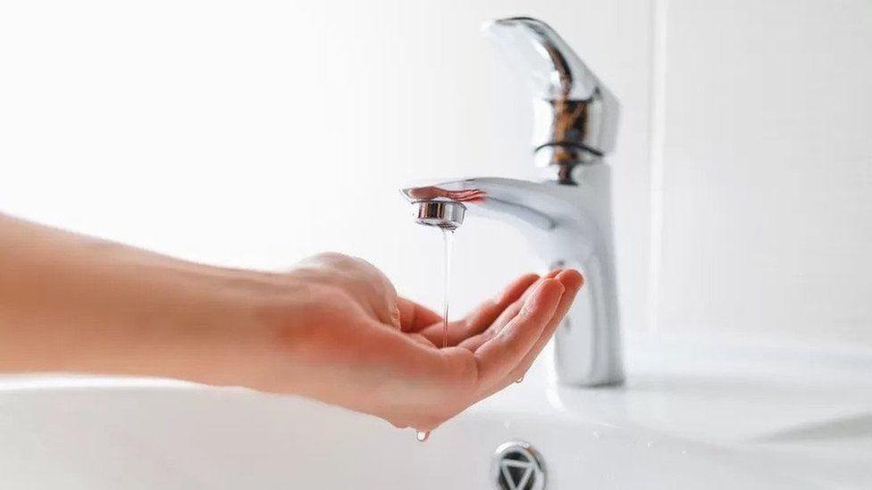 Water running from a tap onto a hand