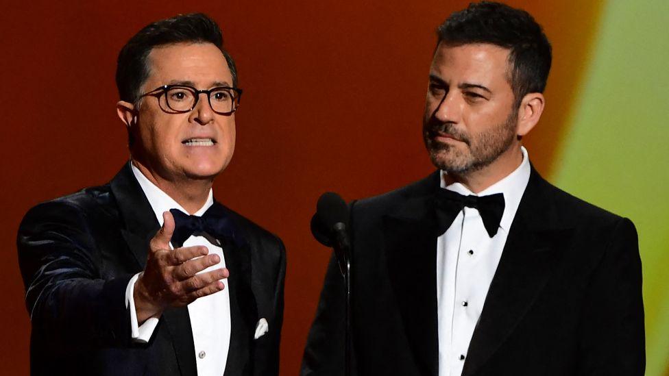 Stephen Colbert (L) and Jimmy Kimmel, both wearing black tuxedos, speak onstage during the 71st Emmy Awards at the Microsoft Theatre in Los Angeles on September 22, 2019