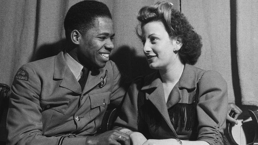 A young couple, a black man in an army uniform and a white woman in a smart coat, in Edinburgh Hall at an evening event held during the Fifth Pan-African Congress, held at Chorlton-upon-Medlock Town Hall in Manchester