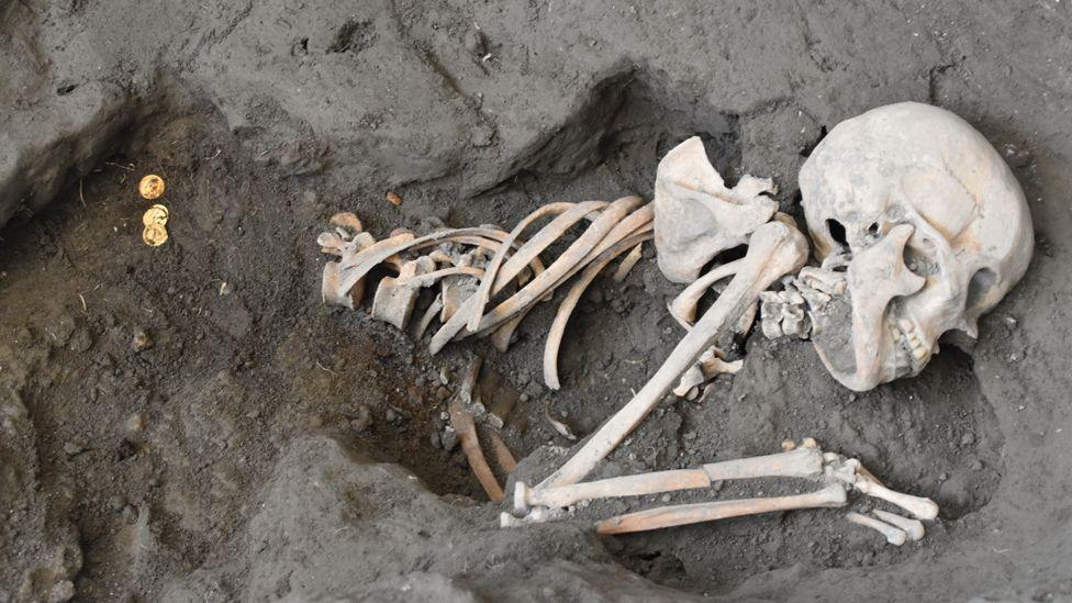 Skeleton of a woman and gold coins