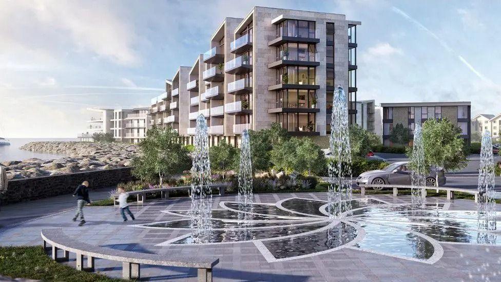 A computer generated image of a circular plaza with fountains, with CGI apartment blocks in the background. A rocky beach can be seen on the left facing the sea. 