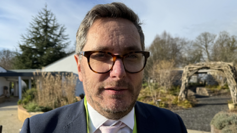 A picture of Irfon Rees looking into the camera. He is standing outside the hospice. 