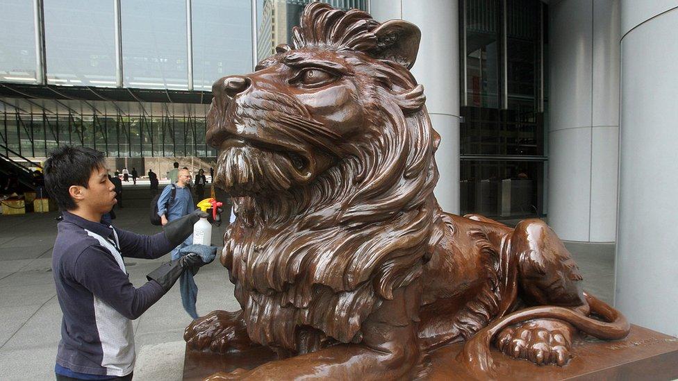 A worker cleans one of the lion statues displayed at the entrance of HSBC bank headquarters in Hong Kong, 05 March 2007