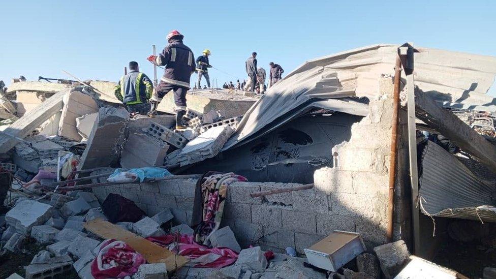 Fire fighters search through the rubble of a house destroyed in a suspected Jordanian air strike in Arman, southern Syria (18 January 2024)