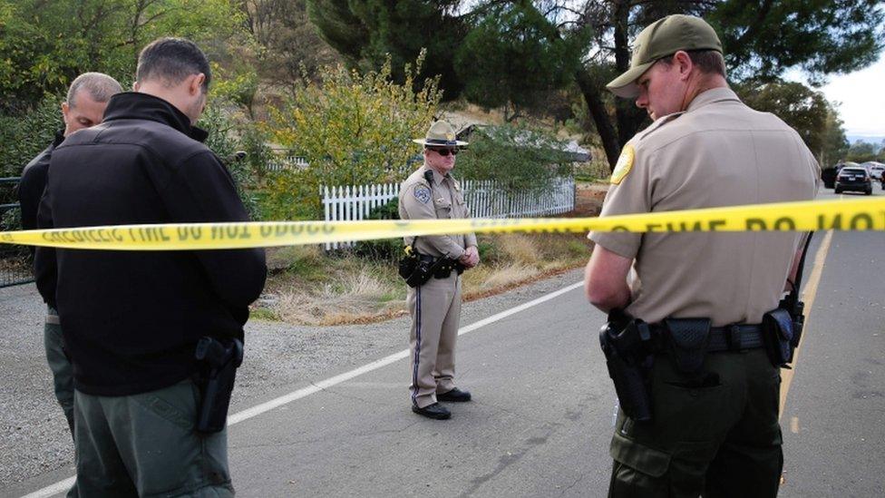 Officers stand near one of the crime scenes of the shooting