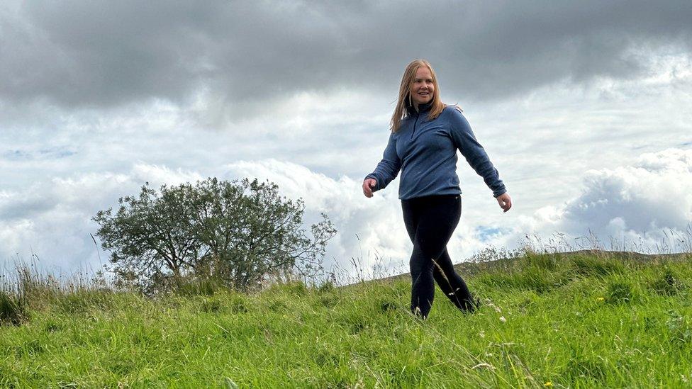 A woman walks through a field