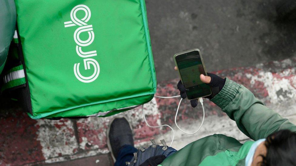 A Grab motorcycle rider checks his mobile phone.