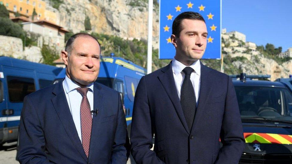 French far-right Rassemblement National (RN) party President Jordan Bardella (R) and RN party member and former head of the EU's border agency Frontex Fabrice Leggeri (L) look on, with a sign reading "Italy" and French gendarmerie vehicles in the background, during a visit at a border crossing between France and Italy in Menton, southeastern France, on February 19, 2024