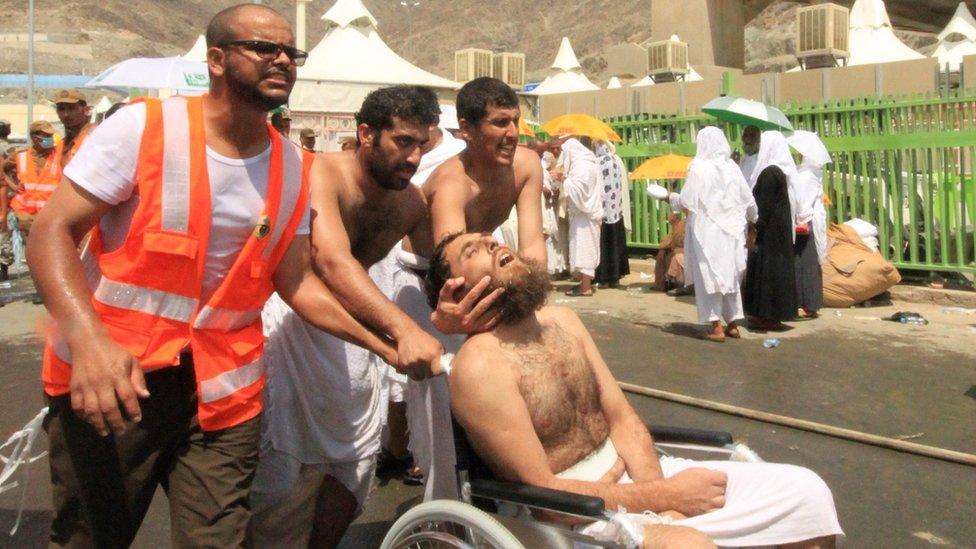 Saudi emergency personnel and Hajj pilgrims push a wounded person in a wheelchair at the site where at least 450 were killed and hundreds wounded in a stampede in Mina, near the holy city of Mecca, at the annual hajj in Saudi Arabia on September 24, 2015.