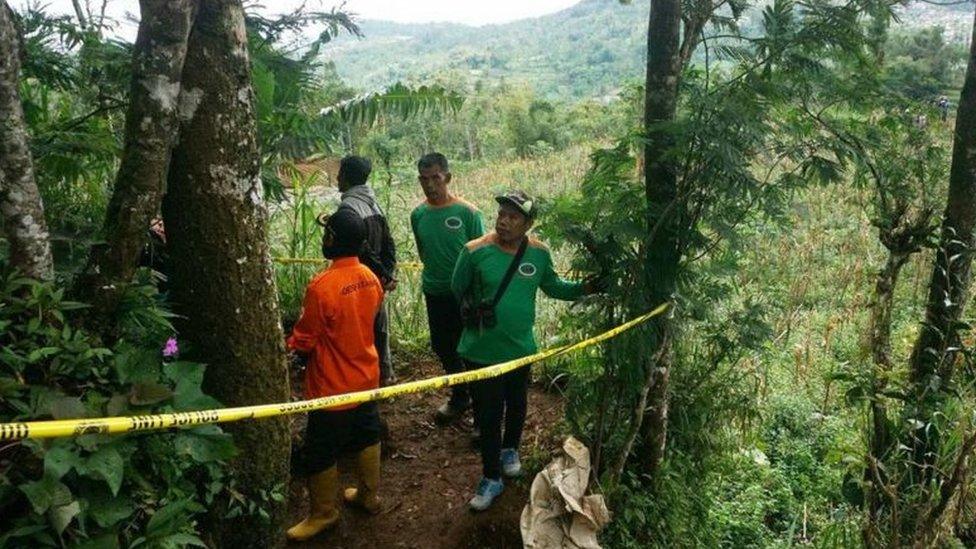 Police workers in the taped-off area of the crime site on a hillside