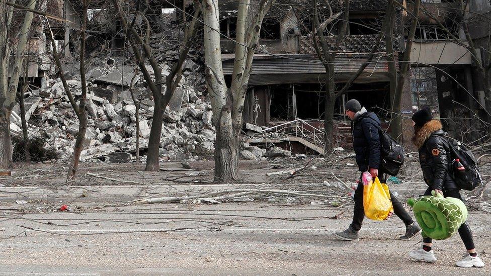 Local residents walk past an apartment building destroyed during Ukraine-Russia conflict in the besieged southern port city of Mariupol, Ukraine March 31, 2022