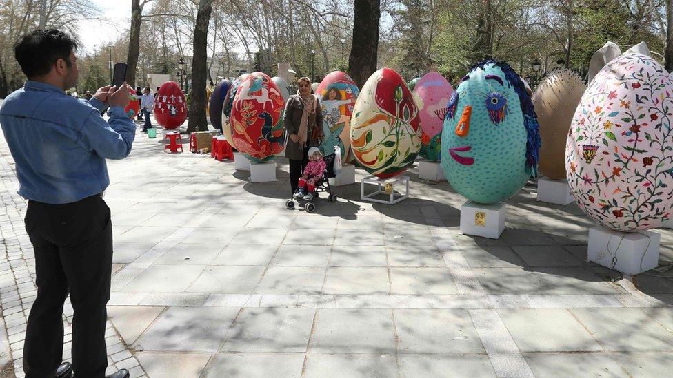 An Iranian man takes a picture of large decorative eggs displayed at the Mellat park during an event organised by the municipality of Tehran on 18 March, ahead of the Persian new year Nowruz.