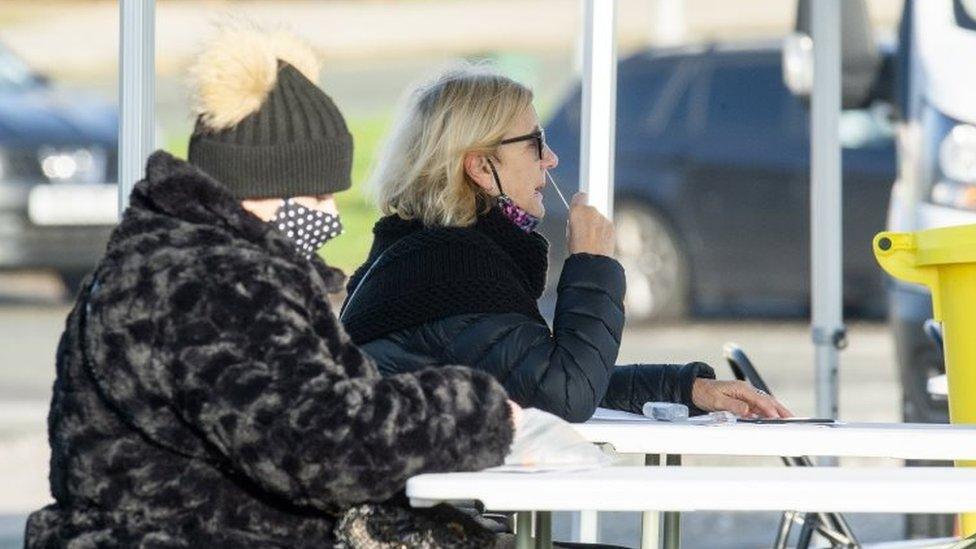 Members of the public conduct to COVID-19 tests outside Wavertree Tennis centre