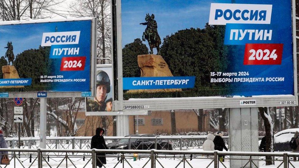 People walk past billboards announcing the 2024 presidential election with slogan 'Russia, Putin 2024' in St. Petersburg