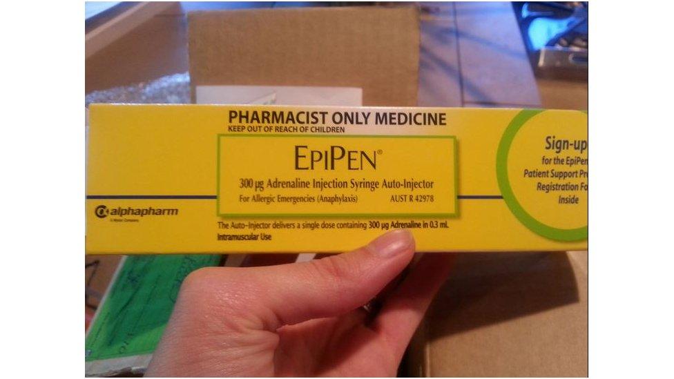 A hand holds the box of an EpiPen Auto-injector which they have just unwrapped.