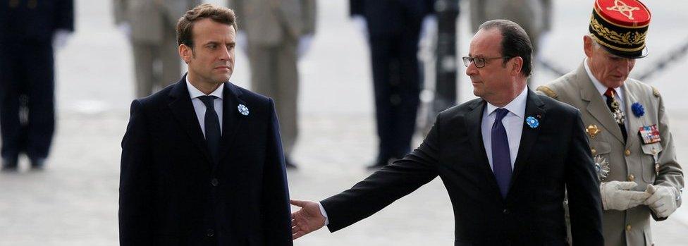 Outgoing French President François Hollande (R) reaches out to touch President-elect Emmanuel Macron, as they attend a ceremony to mark the end of World War II at the Tomb of the Unknown Soldier at the Arc de Triomphe on 8 May