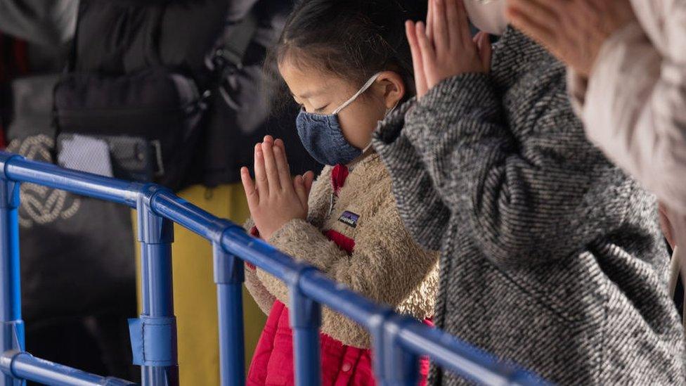 A child is seen praying among the crowds during Hatsumode at the Meiji Jingu Shrine in Shibuya.