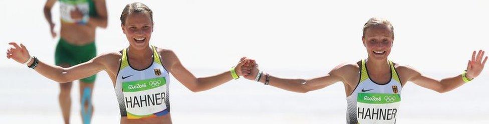 Anna Hahner (L) and her sister Lisa holding hands as they approach the finish line