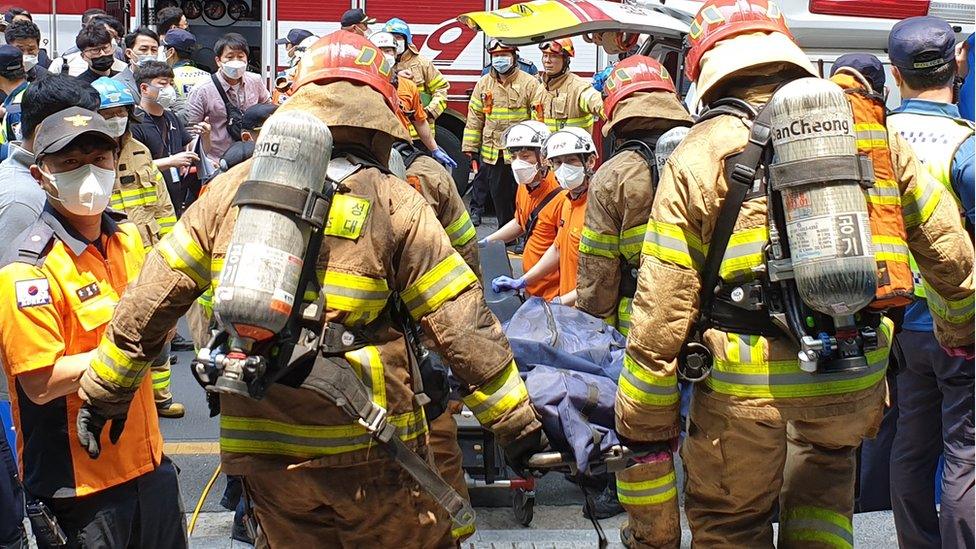 Firefighters carry a body bag on a stretcher out of the building in Daegu