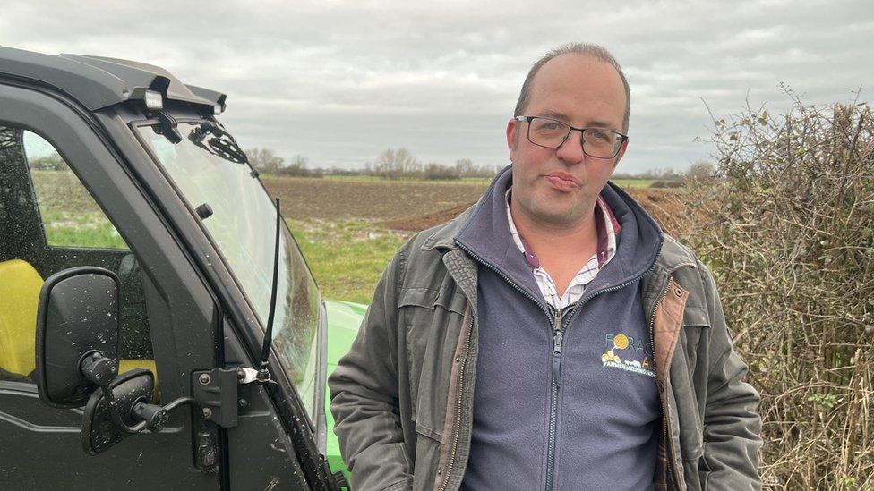 Man stood next to tractor in field