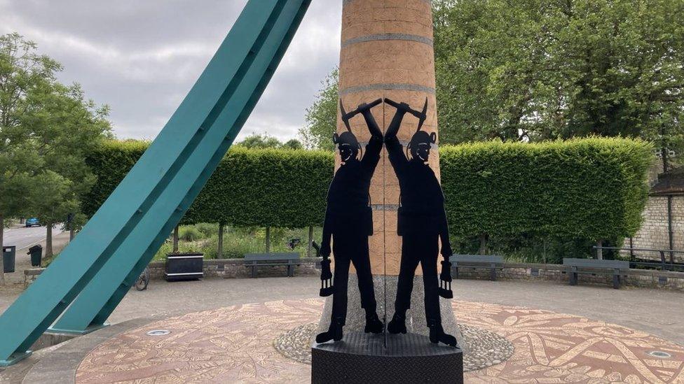 Two figures of coal miners outside the Old Winding Wheel in Radstock