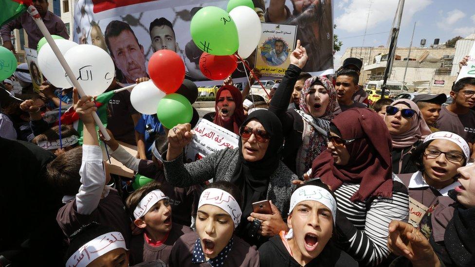 Palestinians holding pictures of prisoners during a rally in Hebron on 4 May 2017