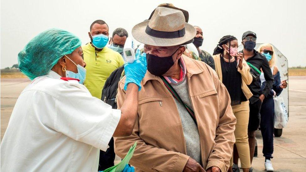 Masked passengers disembarking a flight in Kinshasa in August 2020 have their temperatures taken.