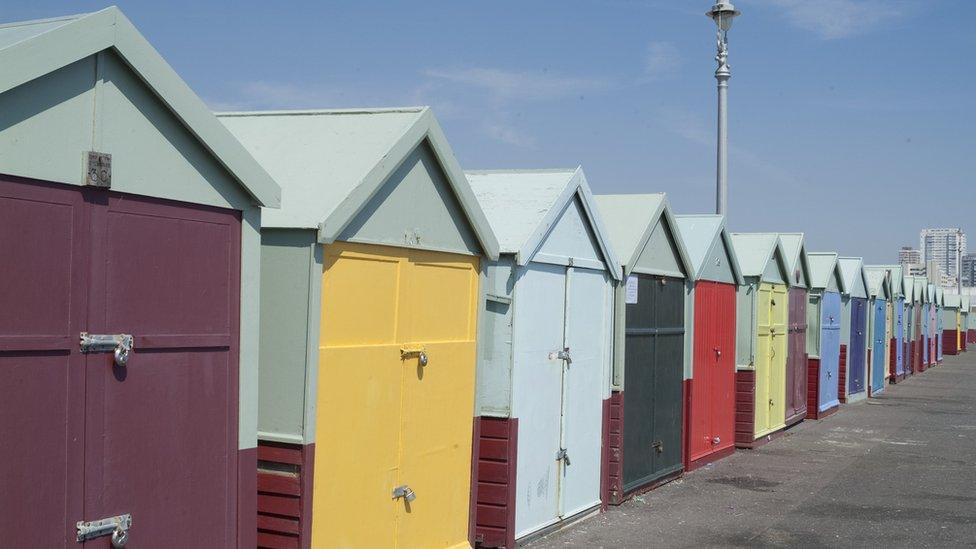 A long row of colourful beach huts on the seafront on the border between Brighton and Hove, East Sussex